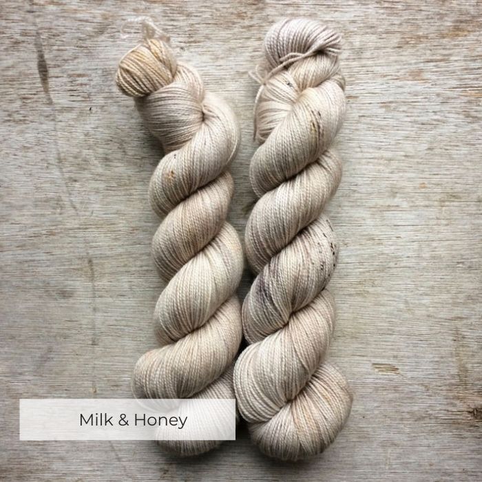 Two skeins of soft yarn in cream, gold and light brown