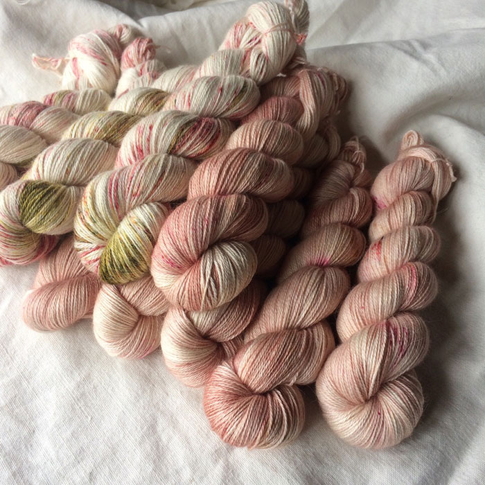 A pile of incredibly soft skeins of pink alpaca yarn laying on a rough linen background