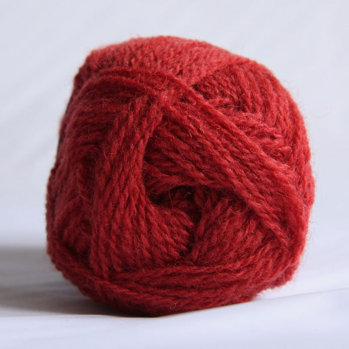 The end of a single ball of shetland wool in a bright coral colour