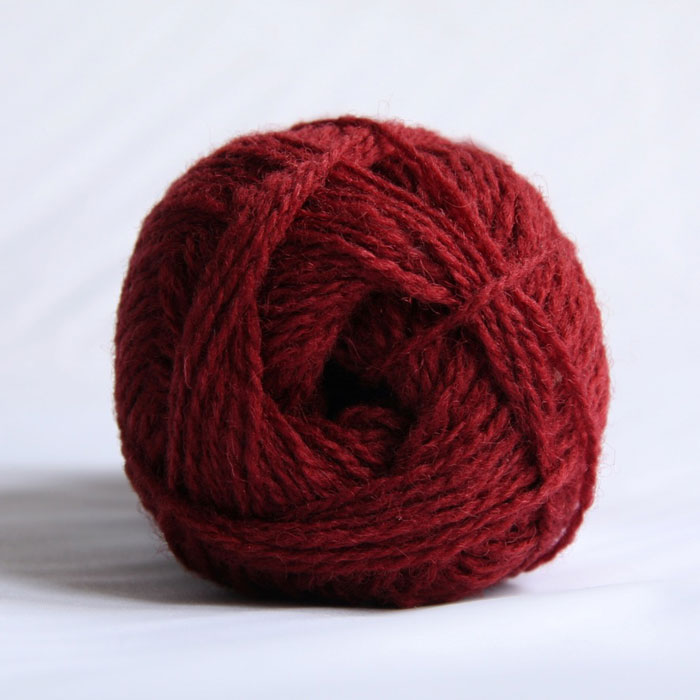 The end of a single ball of shetland wool in a deep red colour