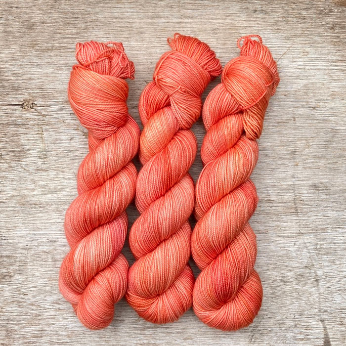 Three skeins of a deep coral yarn