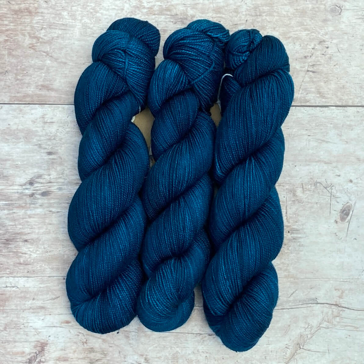 Three skeins of Classic Sock wool in a rich dark teal blue