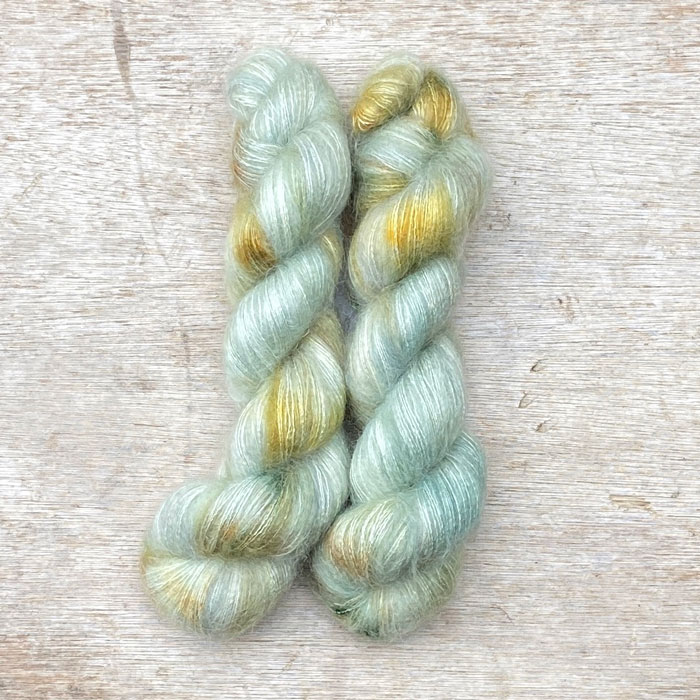 Two skeins of fluffy mohair in pale mint with gold splashes