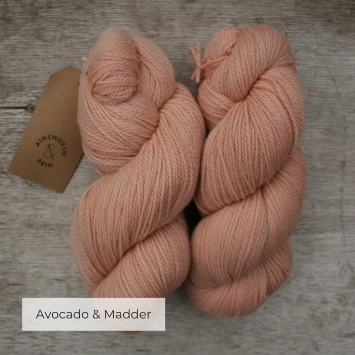 Two skeins of soft pink peach yarn with a brown tie tag