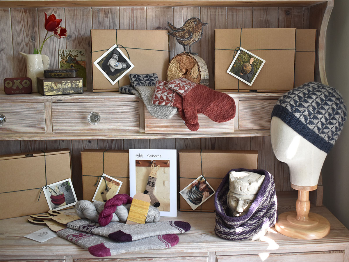 A close up of a kitchen dresser set out with knitting kits in brown boxes and samples