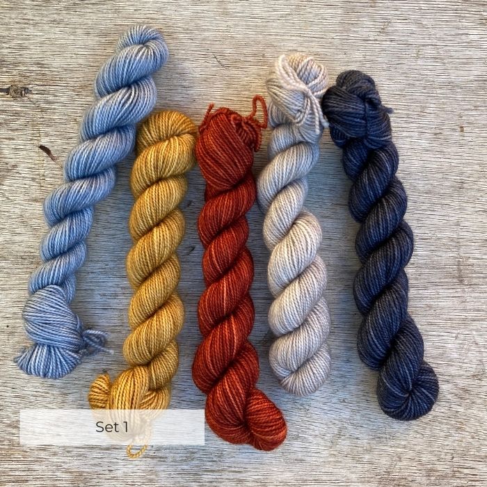 Five mini skeins of sock wool in blue, mustard, burnt red pale fawn and navy