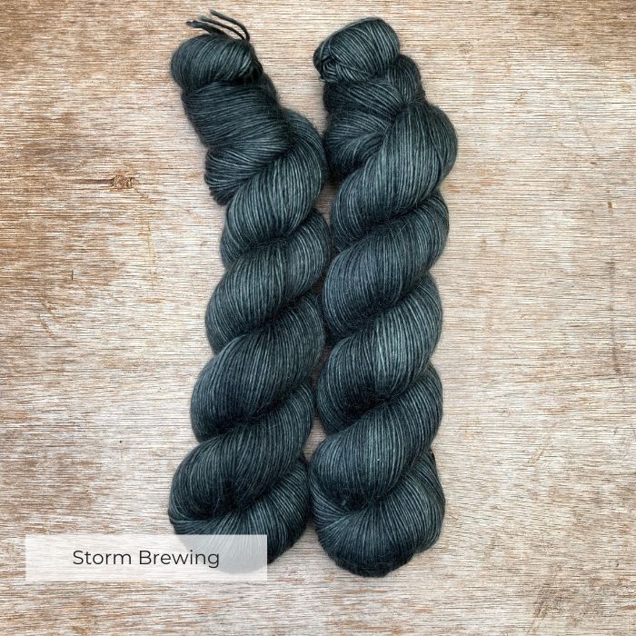 To skeins of soft lightly fluffy yarn in a grey stormy teal