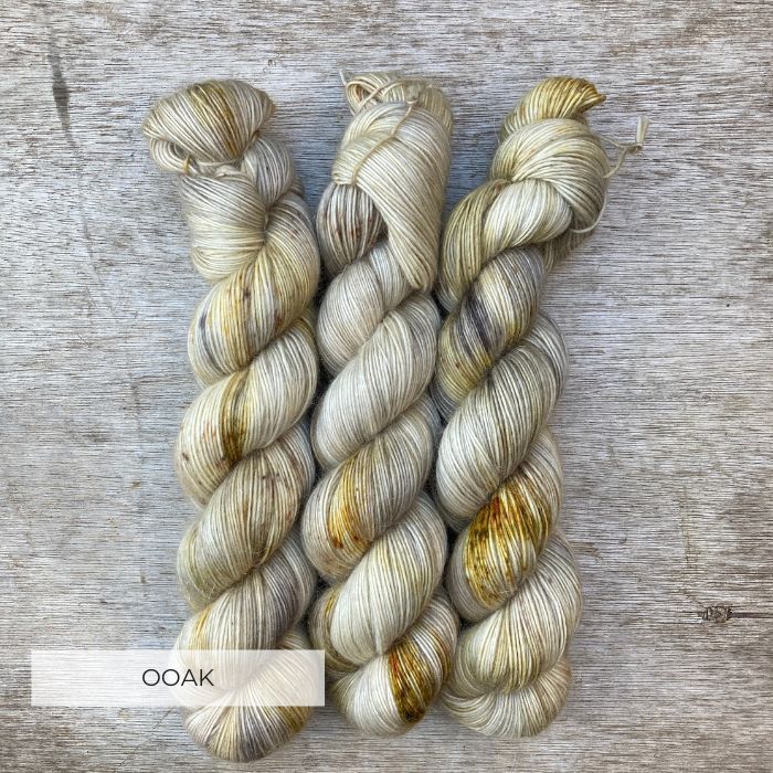 Three skeins of wool in cream, gold and grey