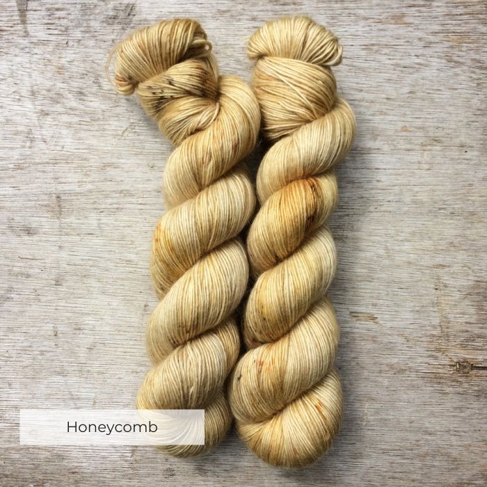 Two skeins of semi solid yellow yarn with speckles of gold and brown