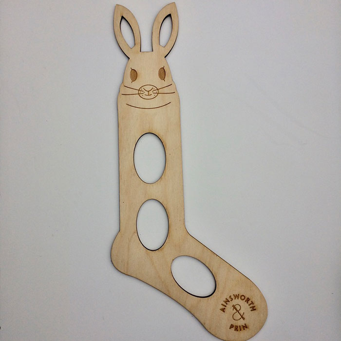 A wooden sock blocker with rabbits' head laying on a white background