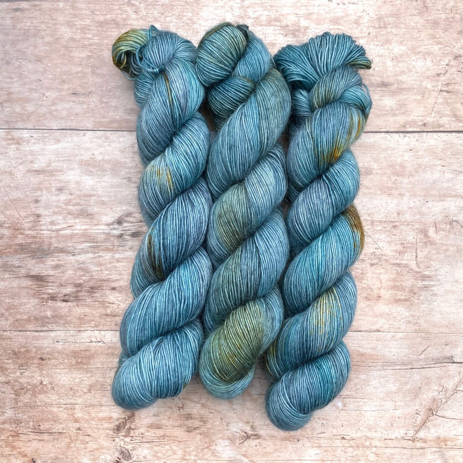 Three skeins of Merino Floof in mid denim blue with golden splashes