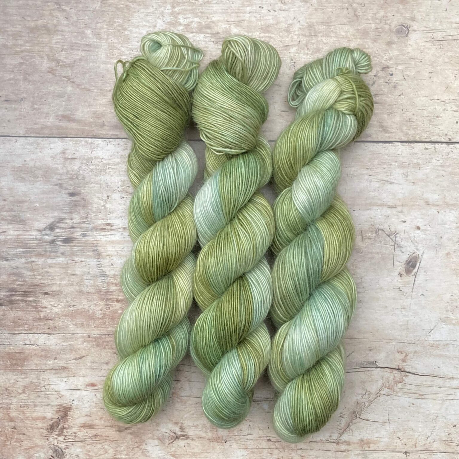 Three skeins of Merino Floof in shades of green and moss