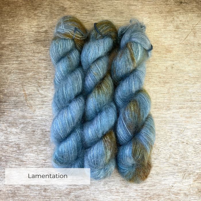 Three skeins of mohair silk lace in mid denim blue with golden splashes