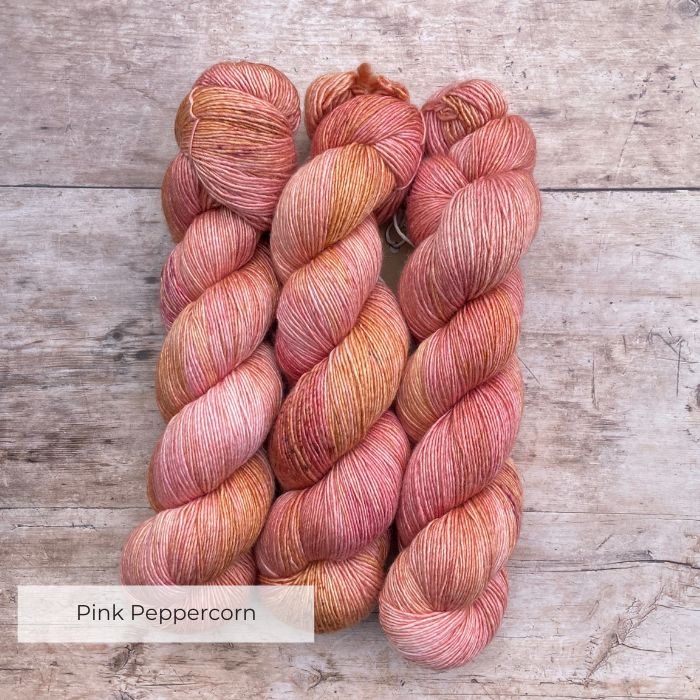 Three skeins of Merino & Silk in peach, coral and mulberry freckled with terracotta and gold