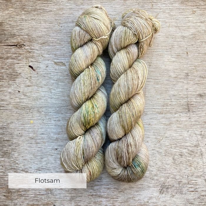 Two skeins of yarn in a neutral stone splashed with moss green