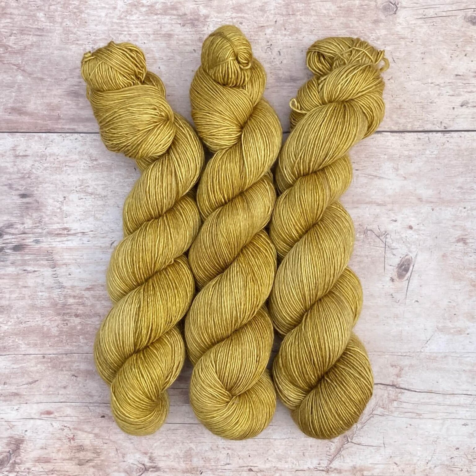 Three skeins of Merino & Silk Single in a light mustard