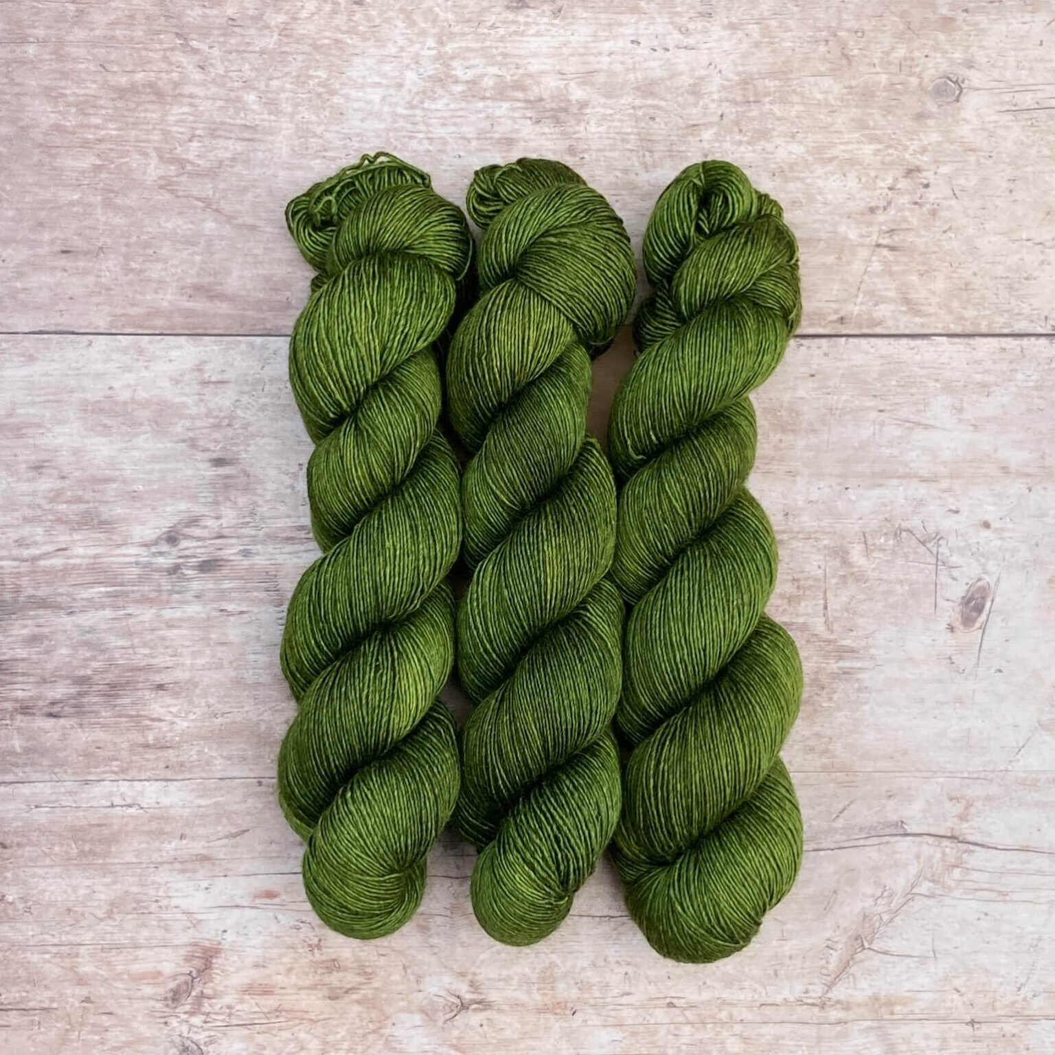 Three skeins of Merino & Silk Single in a forest green