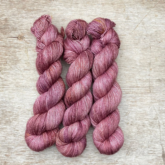 Three skeins of merino silk yarn in pinks and golds
