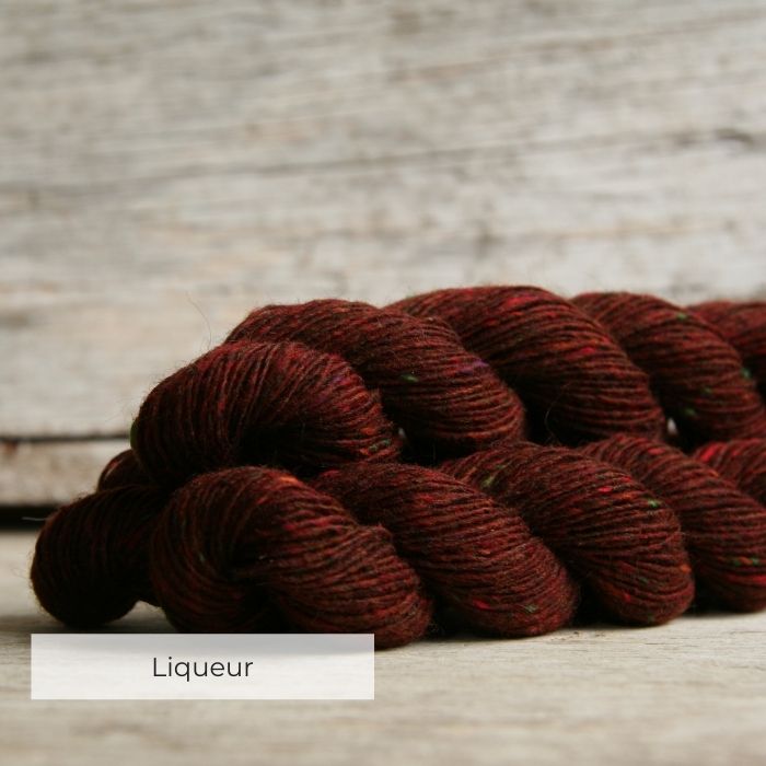 Three skeins of of deep red yarn with tweedy naps of green, red and charcoal