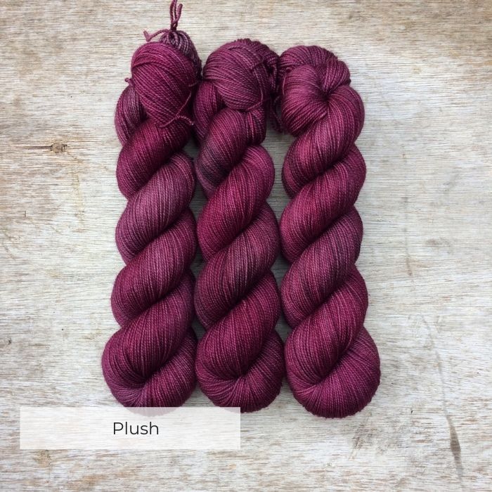 Three skeins of yarn the colour of faded burgundy and plum