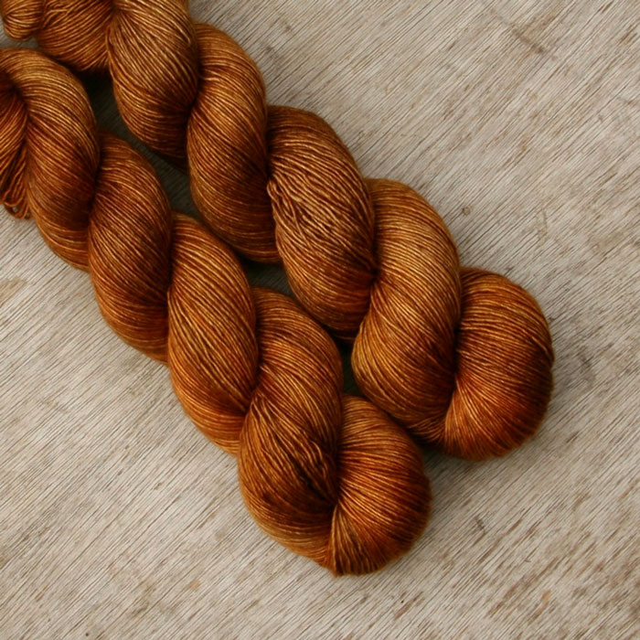 Two skeins of semi solid sock yarn that have been dyed in shades of toffee
