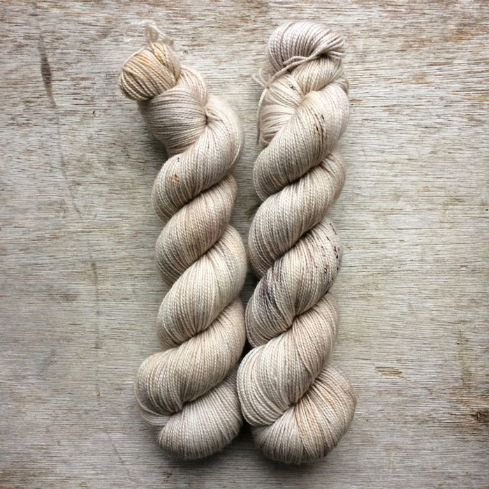 Two skeins of soft yarn in cream, gold and light brown