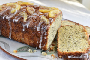 A lemon poppy seed cake on a plate with a slice taken off