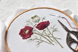 An embroidery of poppies in a ring with some black scissors