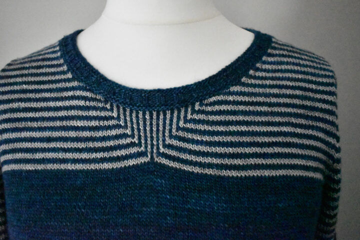 A close up of the neckline of a stripped knitted T-shirt showing a slip stitch pattern