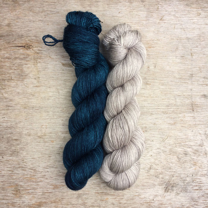 Two skeins of silky merino yarn one in a deep blue and the other a pale grey