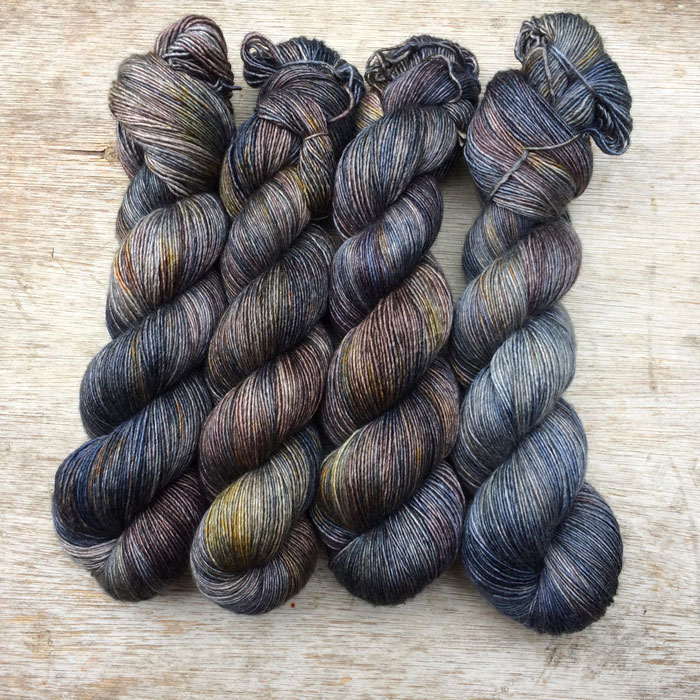 Four hanks of slightly silky yarn in shades of blue, brown, gold and plum