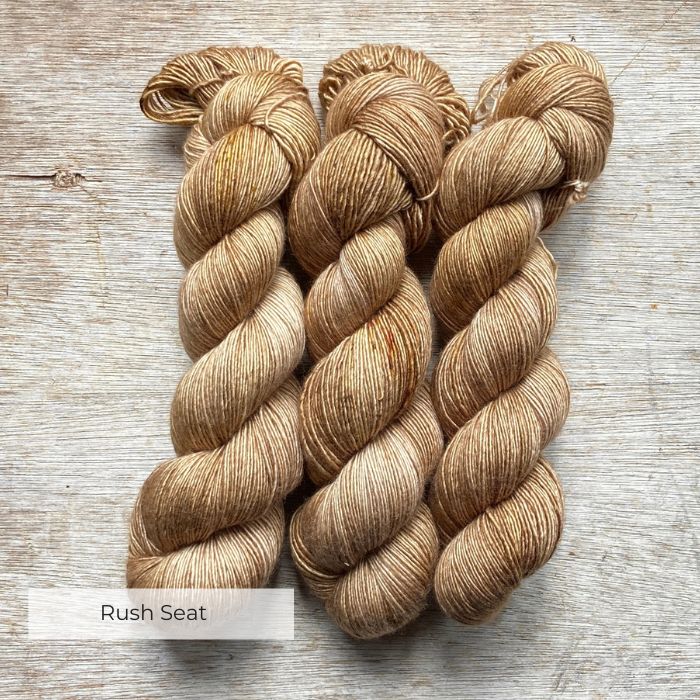 Three skeins of silky yarn in shades of soft caramel