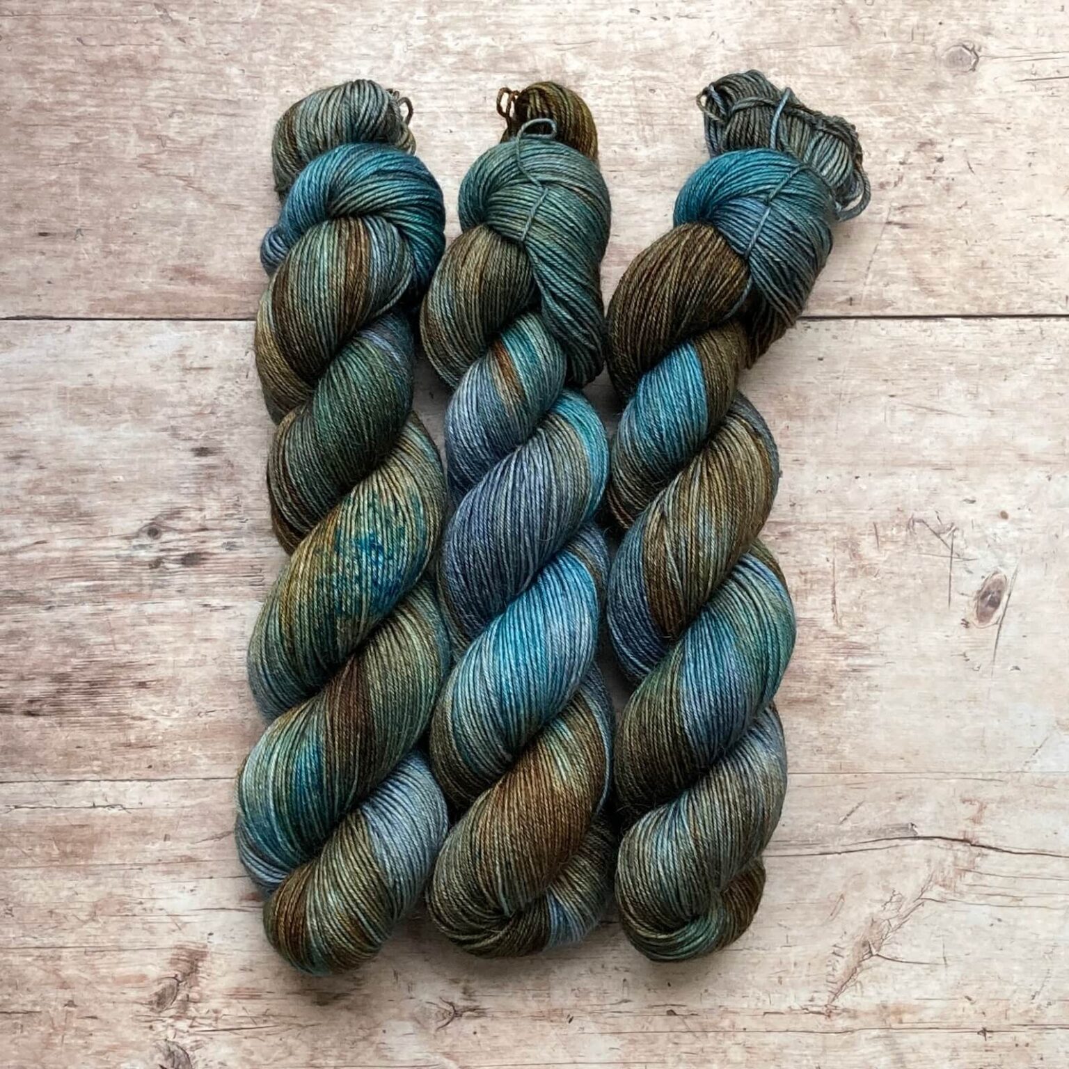 skeins of merino and mohair sock yarn in golden brown, denim and turquoise
