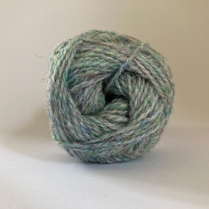 Close up of the end of a ball of wool in a soft marled blue green
