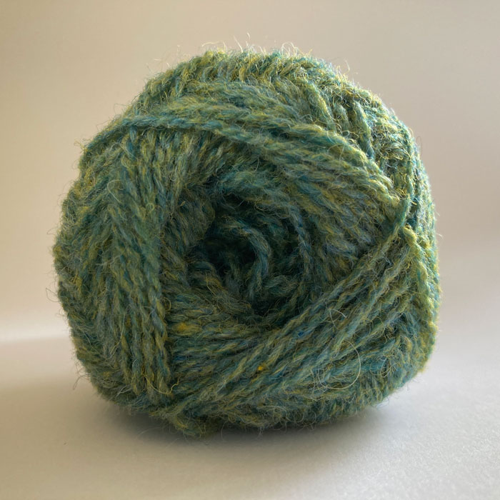 Close up of the end of a ball of wool in a soft marled green
