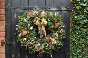 An evergreen wreath with hand dyed silk ribbons on an old wooden door