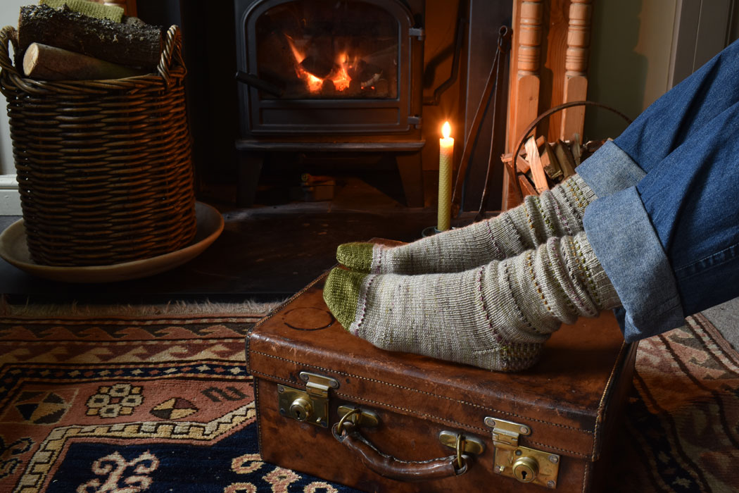 Feet in hand knit socks in front of a fire