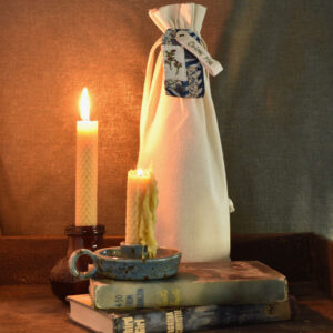 A sister scene of a pile of books and candles with a wrapped bottle labelled Drink Me