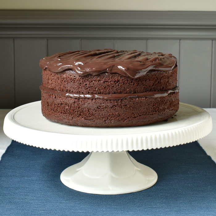 A rich chocolate cake on a white cake stand