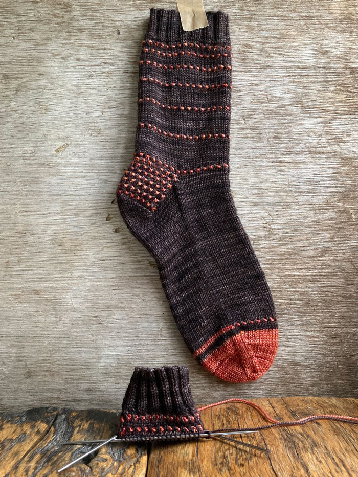 A dark brown sock with orange stripes