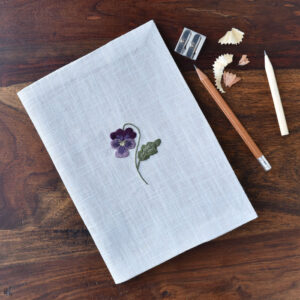 A notebook embroidered with a small viola