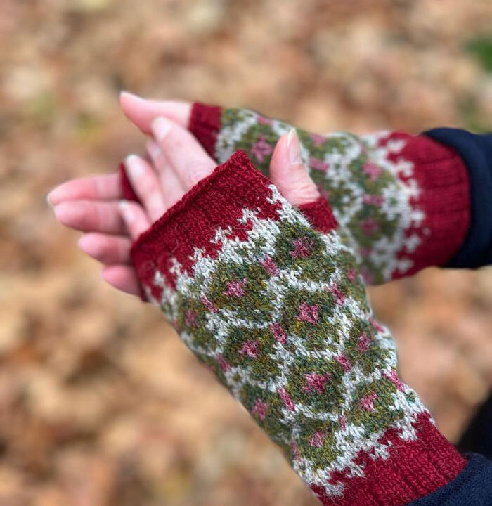 A pair go fingerless fair isle mittens in a cheery red on some very cold fingers