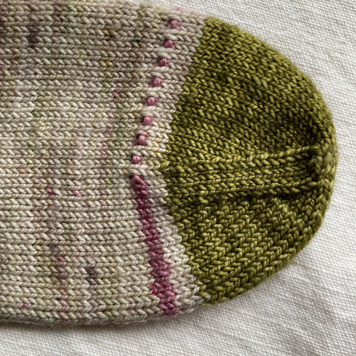 A close upon the toe of a sock with one row of pattern and a green toe