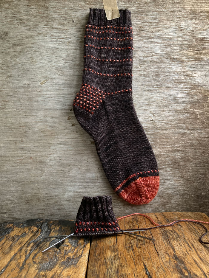 A browning orange sock hanging against a wooden background