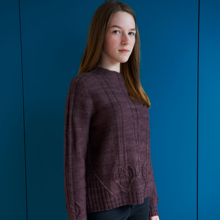A young girl wearing a purple cabled jumper