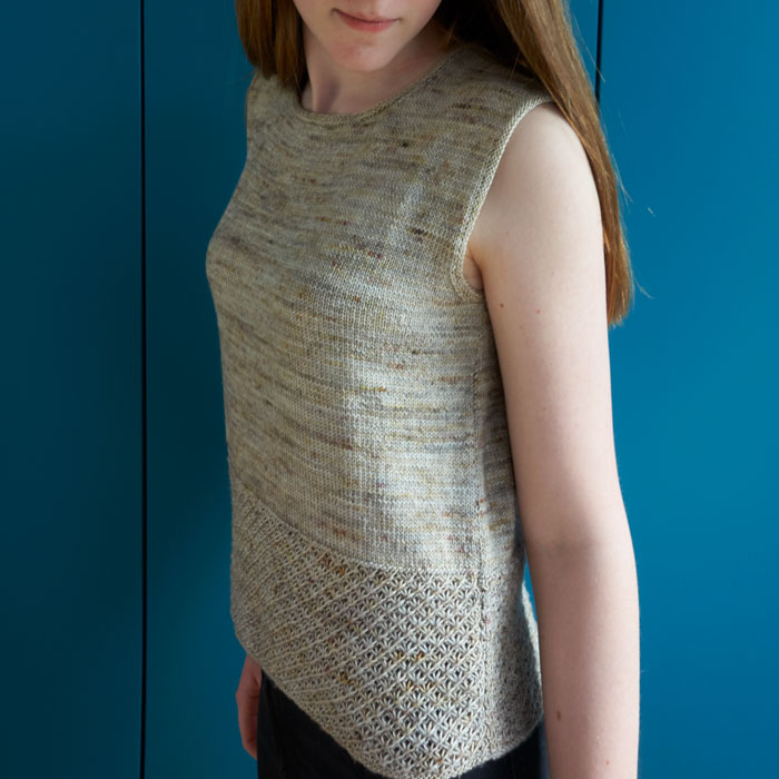 A young girl wearing a sleeveless hand knitted top