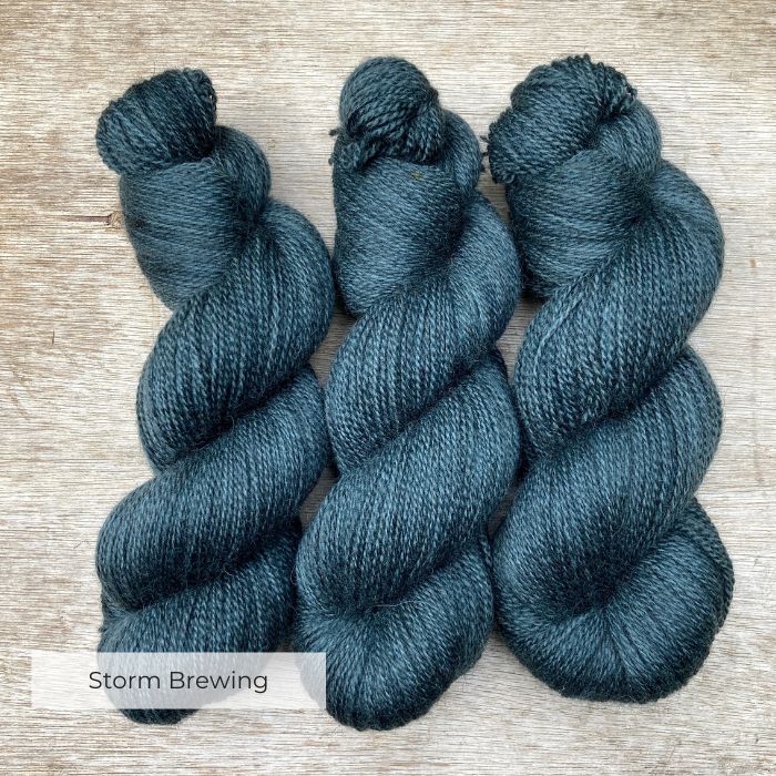 Three plump skeins of British wool in a moody grey blue