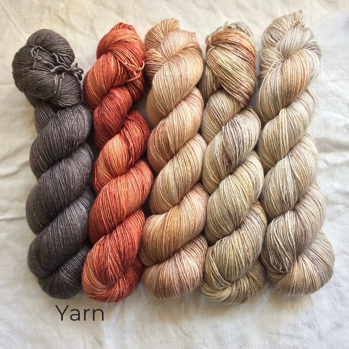 Five skeins of hand dyed yarn on a rumpled cloth