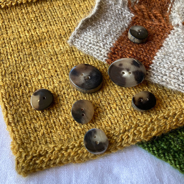 A scattering of natural horn buttons on knitted swatches
