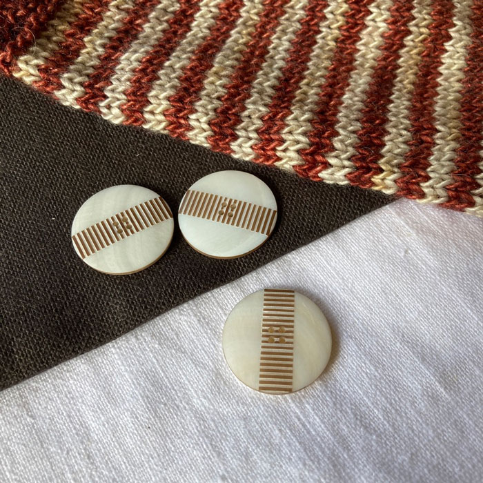 Three large white shell buttons with layered brown stripes